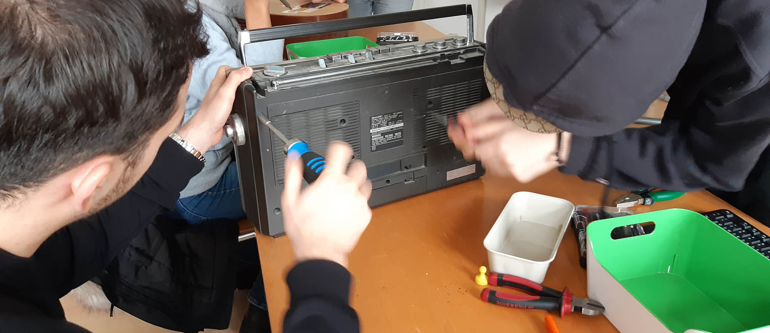 2 Jugendliche schrauben die Rückseite eines Radios auf.